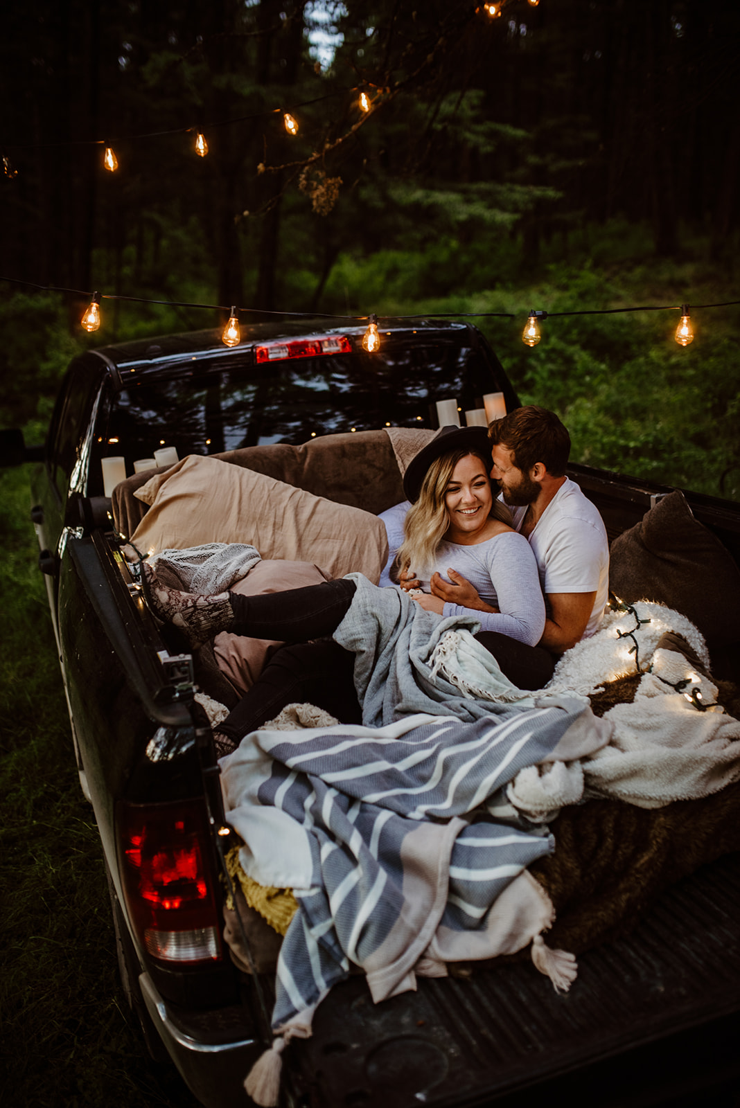 couple in truck bed cozy with blankets and lights
